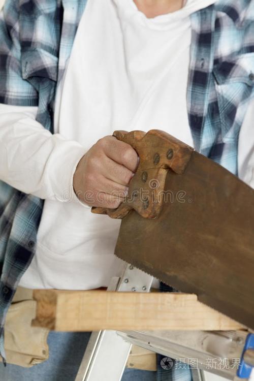 着工具带的人漂亮的木匠在工作圆锯切木板木工电锯木很多工具测量愤怒